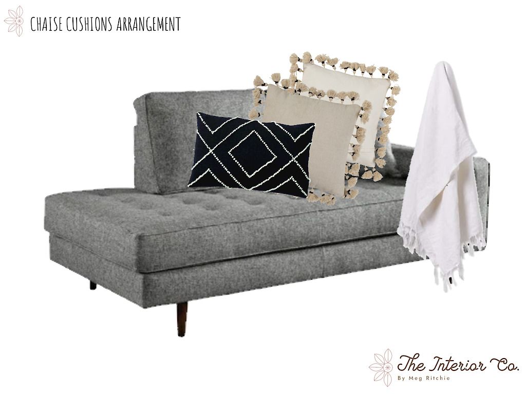 A grey chaise lounge with pillows and a white blanket