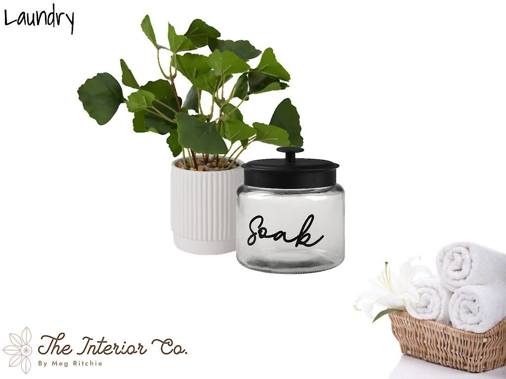 A jar of soak next to a potted plant and a basket of towels.