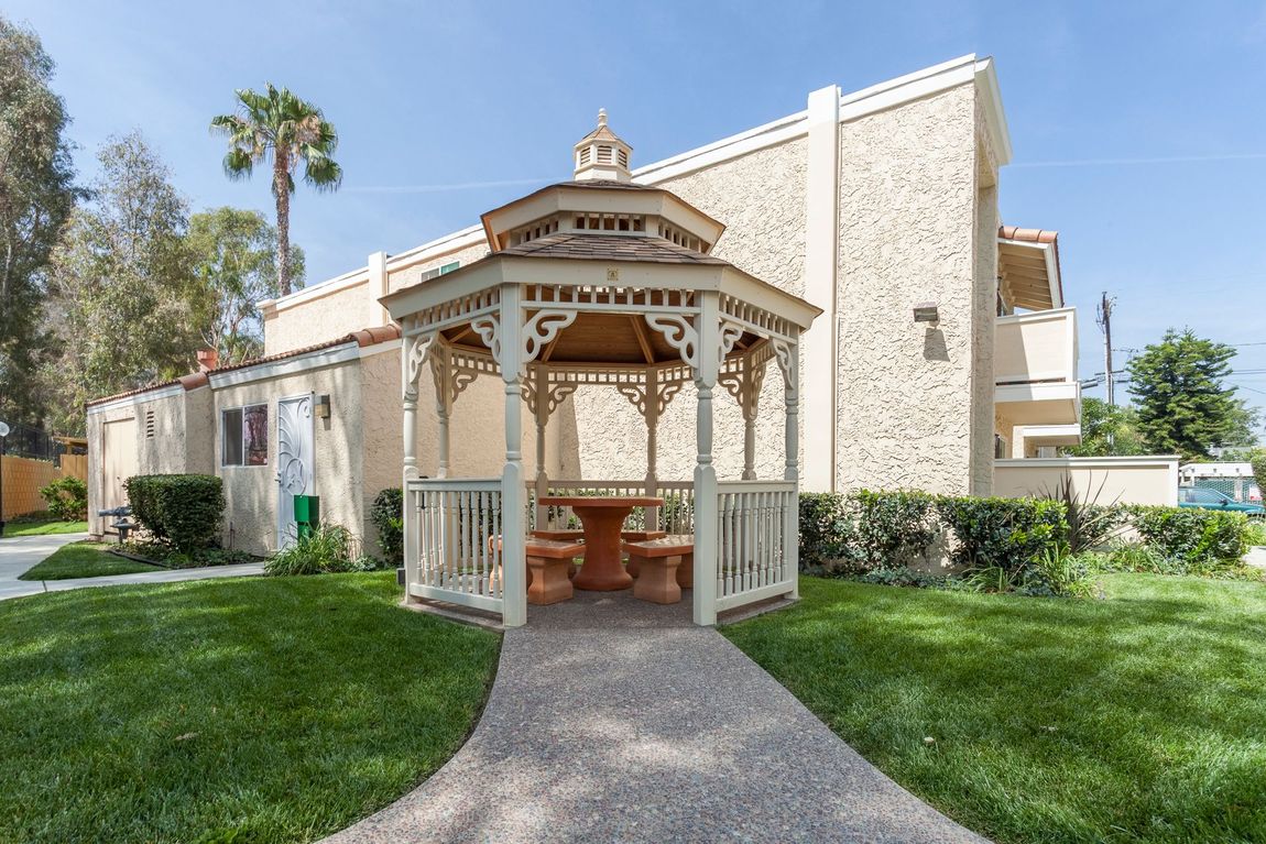 A gazebo with a table and chairs in front of a building.