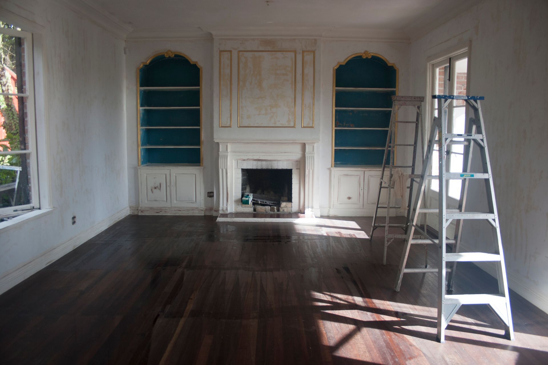 An empty living room with a fireplace and shelves