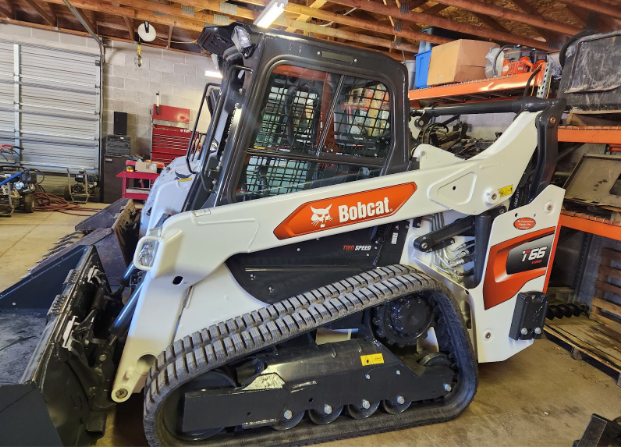 A bobcat track loader is parked in a garage.