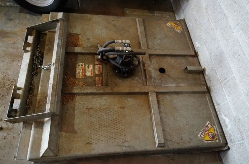 A metal box with a hose attached to it is sitting on a cement floor.