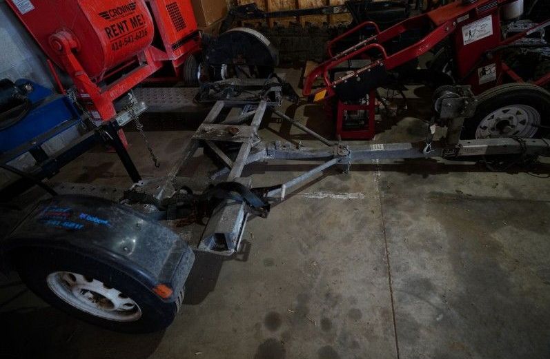 A trailer is sitting in a garage next to a tractor.