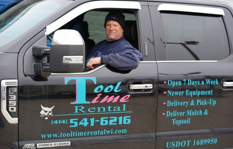 A man is driving a tool time rental truck