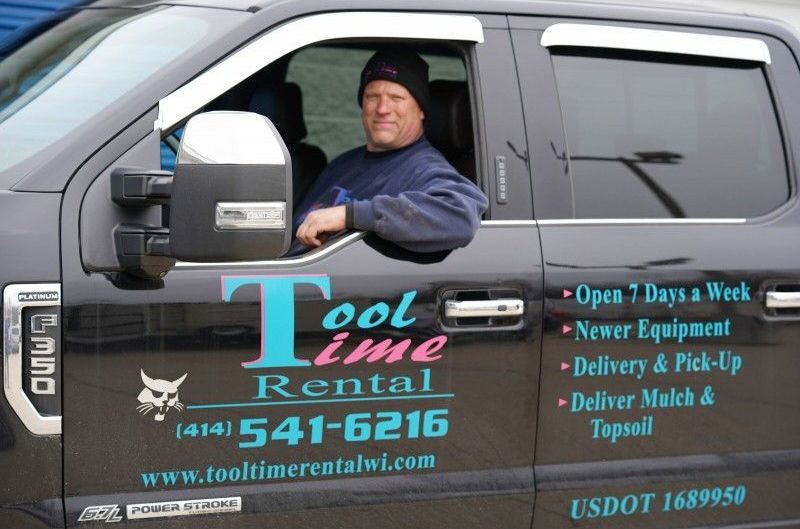 A man is sitting in the driver 's seat of a tool time rental truck