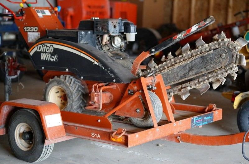 A ditch witch trencher on a trailer in a garage
