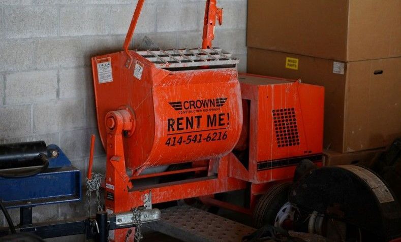 A concrete mixer is sitting in a room next to a brick wall.