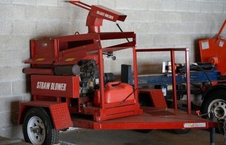 A red trailer with a straw blower on it