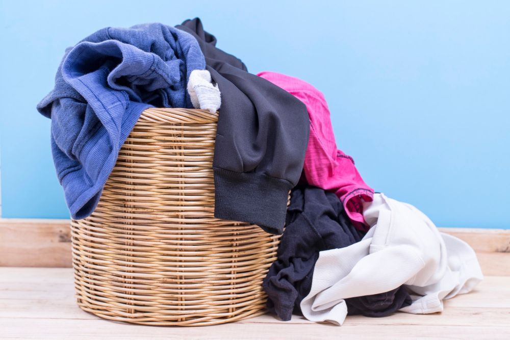 a wicker laundry basket filled with clothes against a blue wall