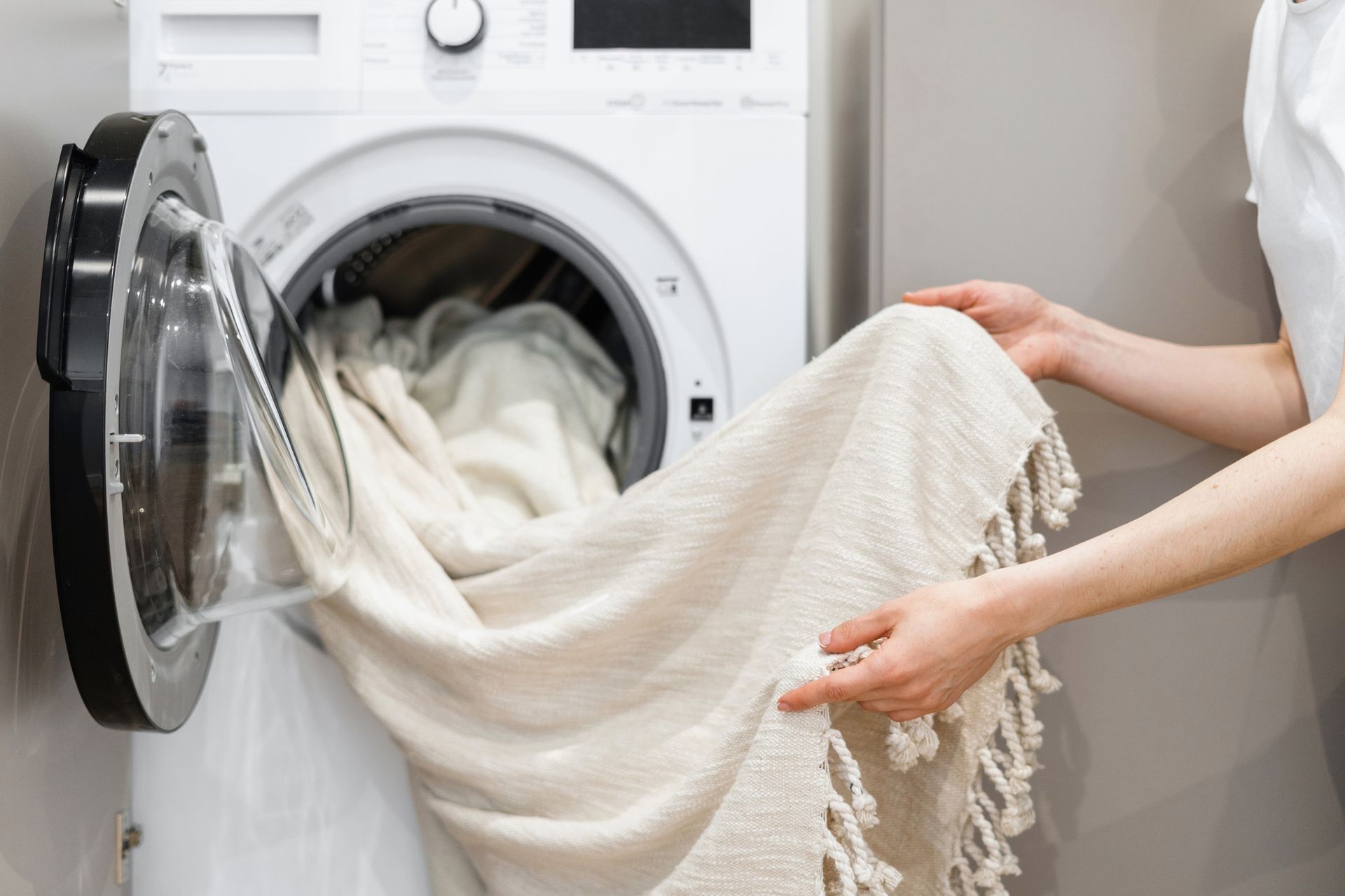 a person is putting a blanket into a washing machine