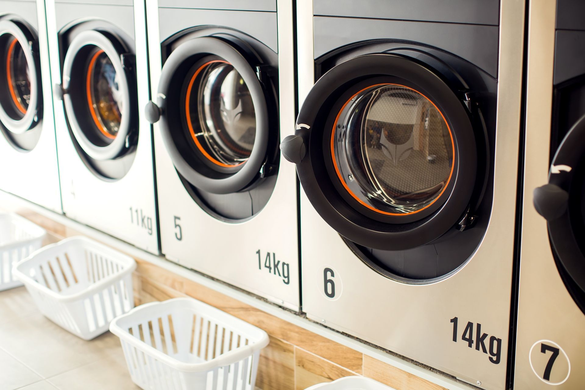 a row of washing machines in a laundromat with baskets .