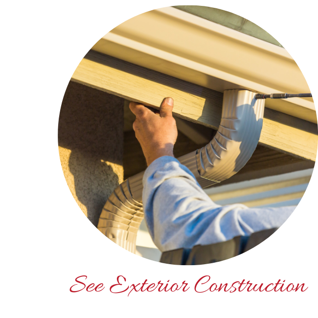 A person in a light blue shirt works on the gutter and fascia board of a building's exterior.