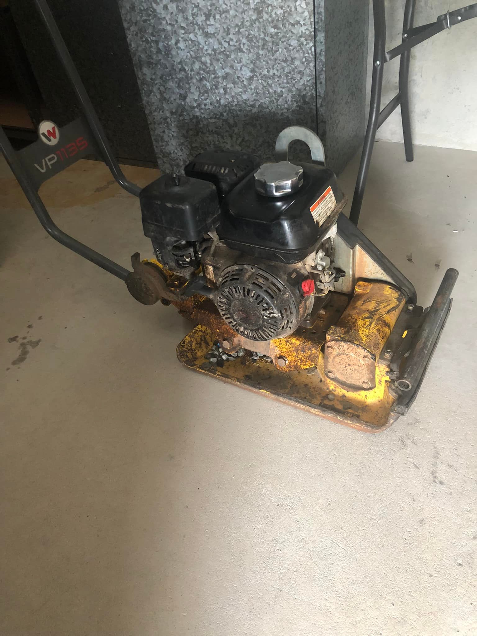 Small black engine on a yellow cart in a garage, with oil or debris around it — Cairns Small Engine Repairs in Bentley Park, QLD