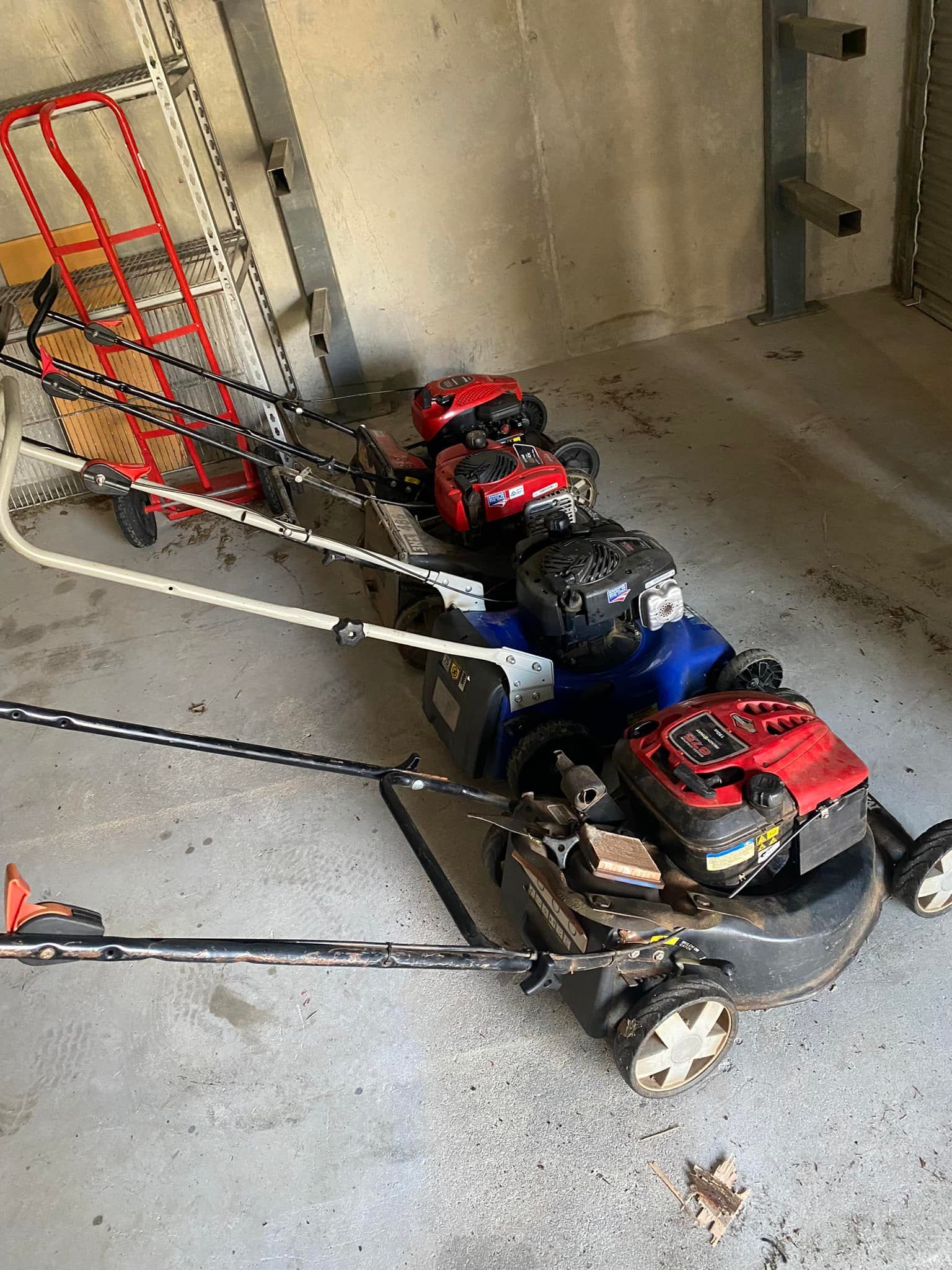 Several Lawnmowers and a Cart Stored in a Concrete Garage — Cairns Small Engine Repairs in Bentley Park, QLD