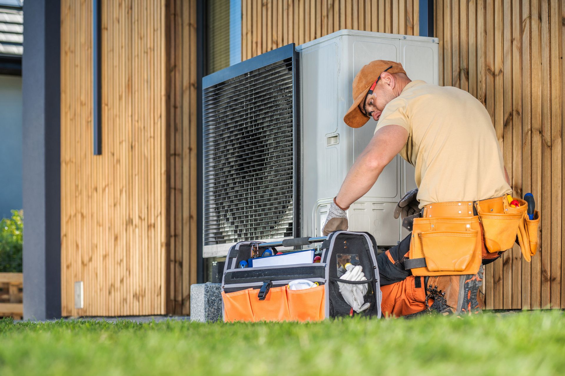 A man is working on a heat pump outside of a house.