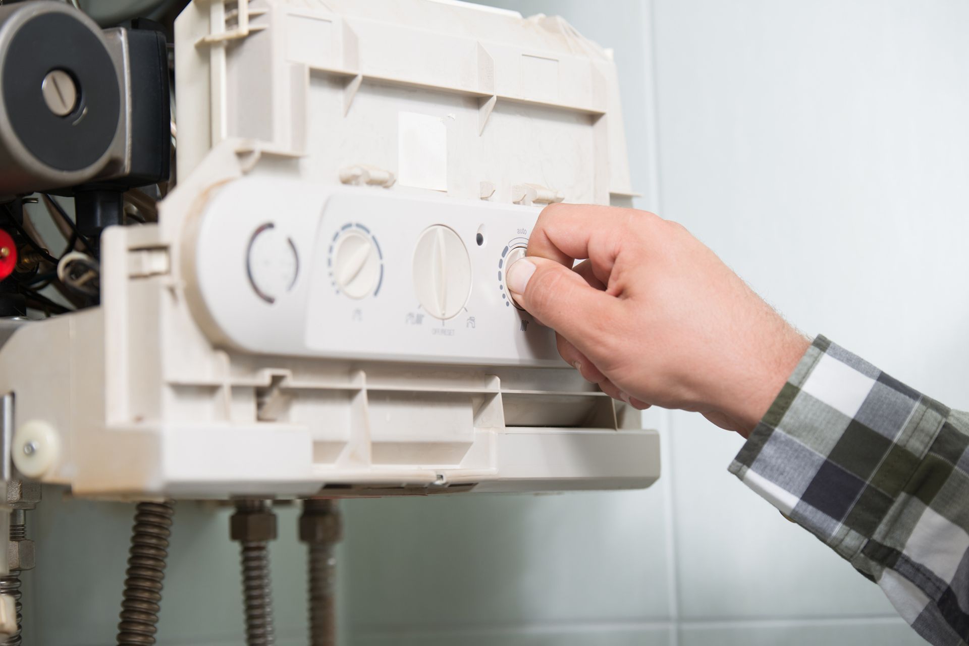 A person is adjusting the temperature of a boiler.