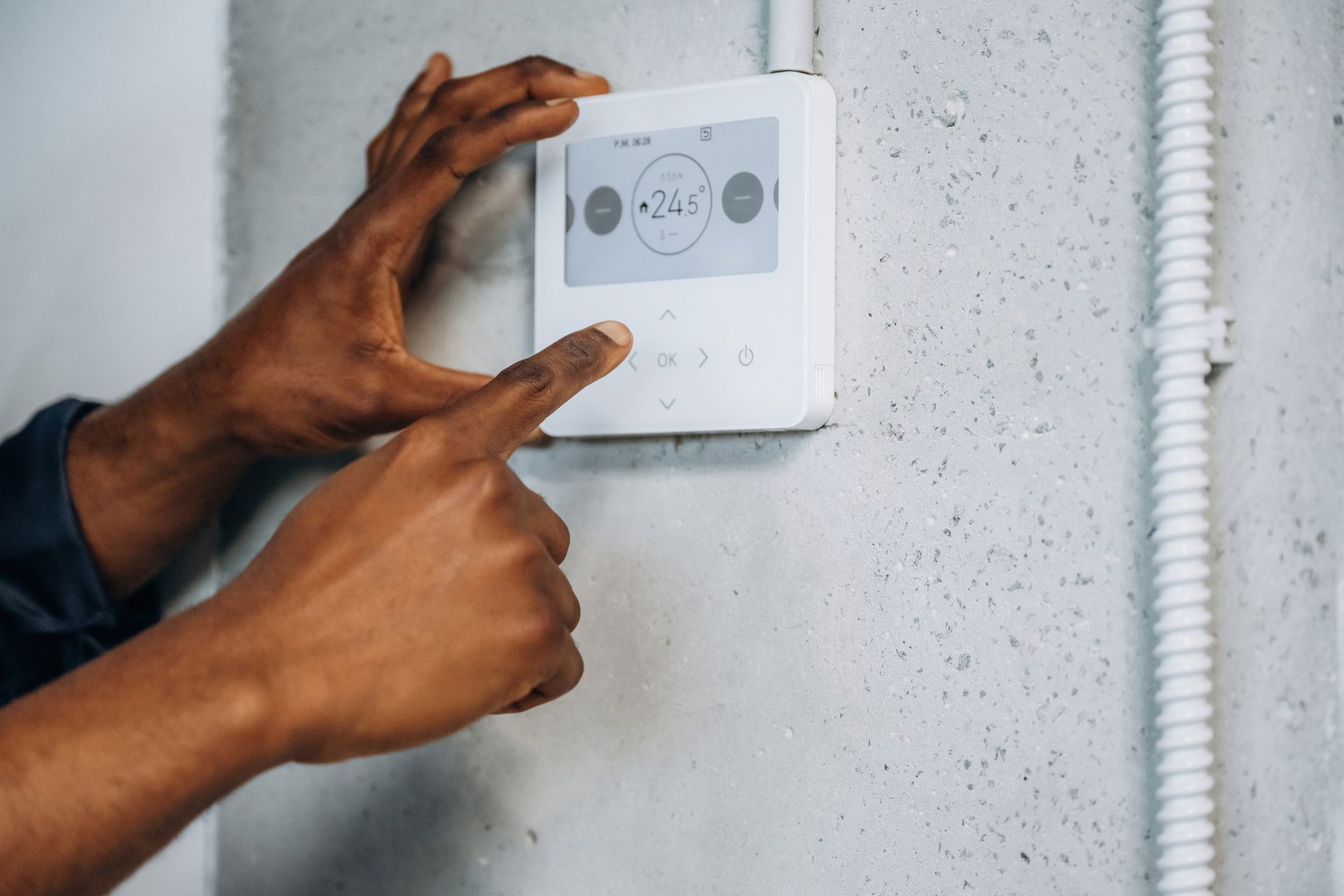 A person is adjusting a thermostat on a wall. A person is adjusting a thermostat on a wall.