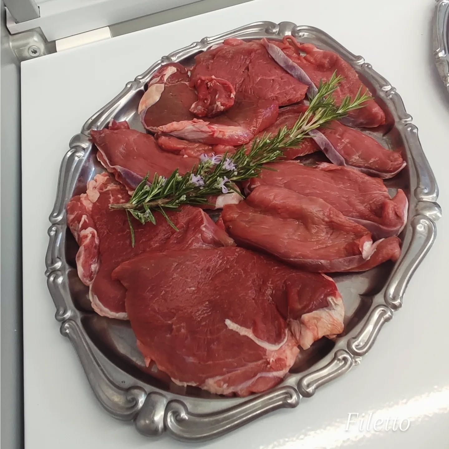 Olive verdi pendono dal ramo di un albero, mentre file di ulivi sfumano nella luce del sole.