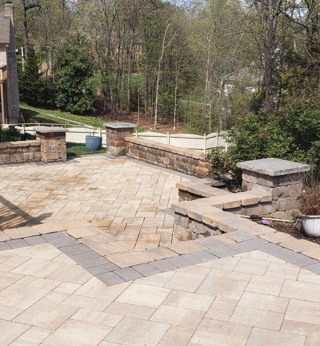 A patio with a stone wall and trees in the background
