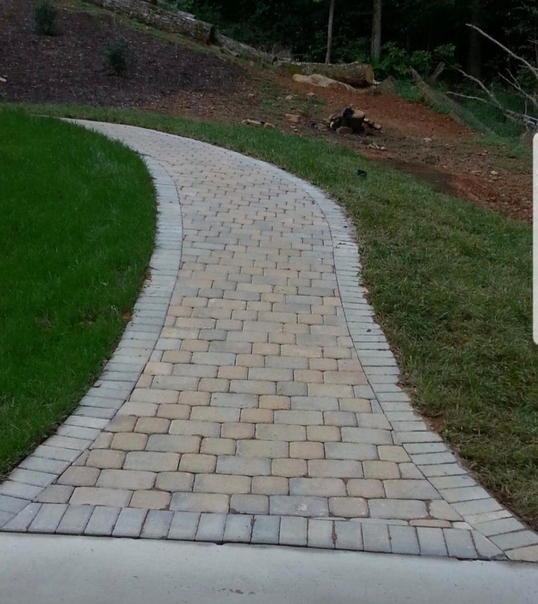 A brick walkway going through a lush green field