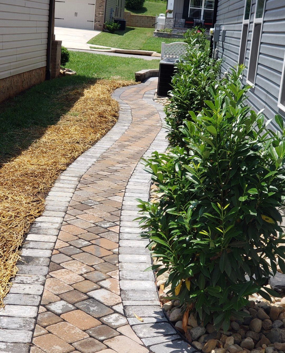 A brick walkway going to the side of a house