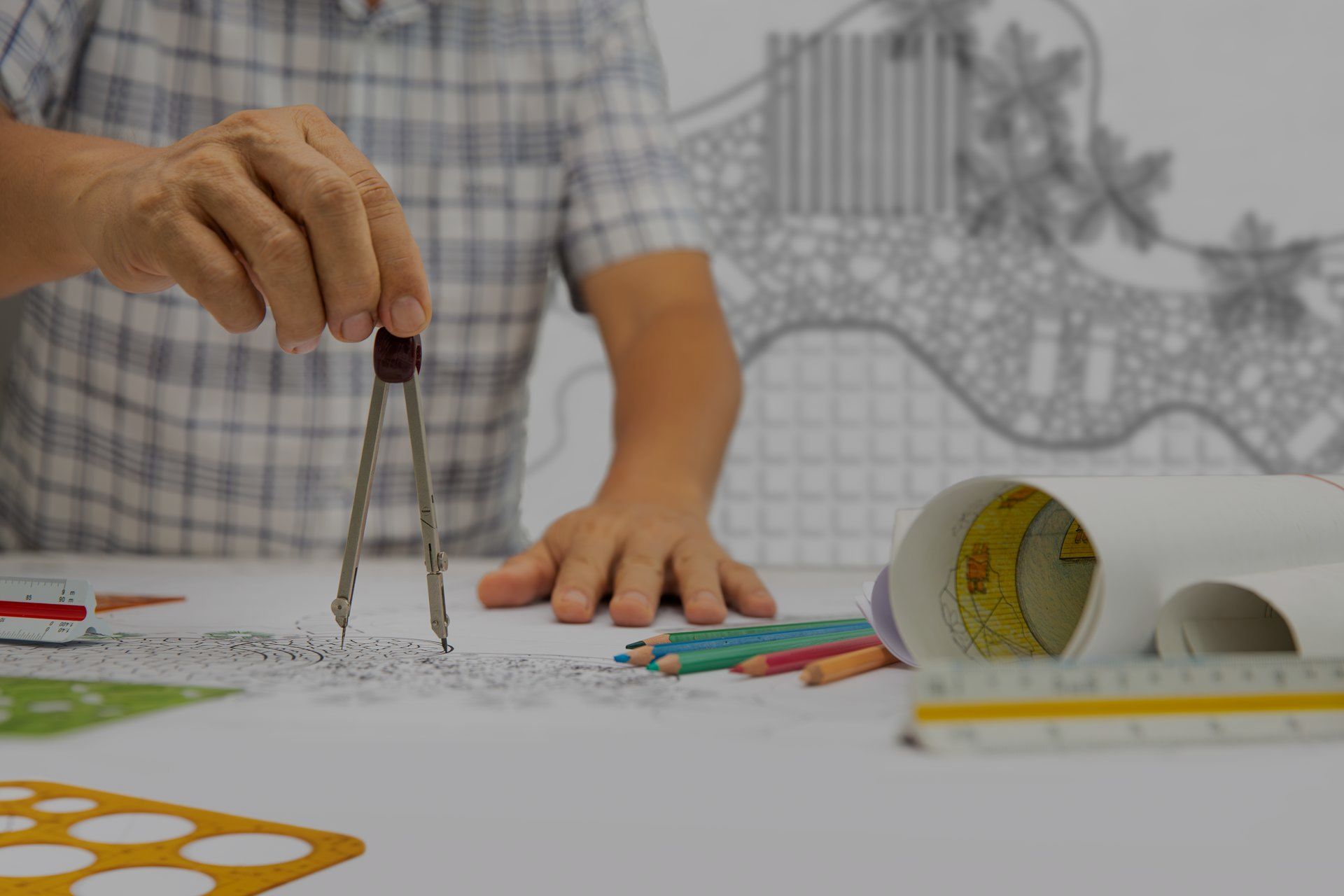 A man is using a compass to draw on a piece of paper.