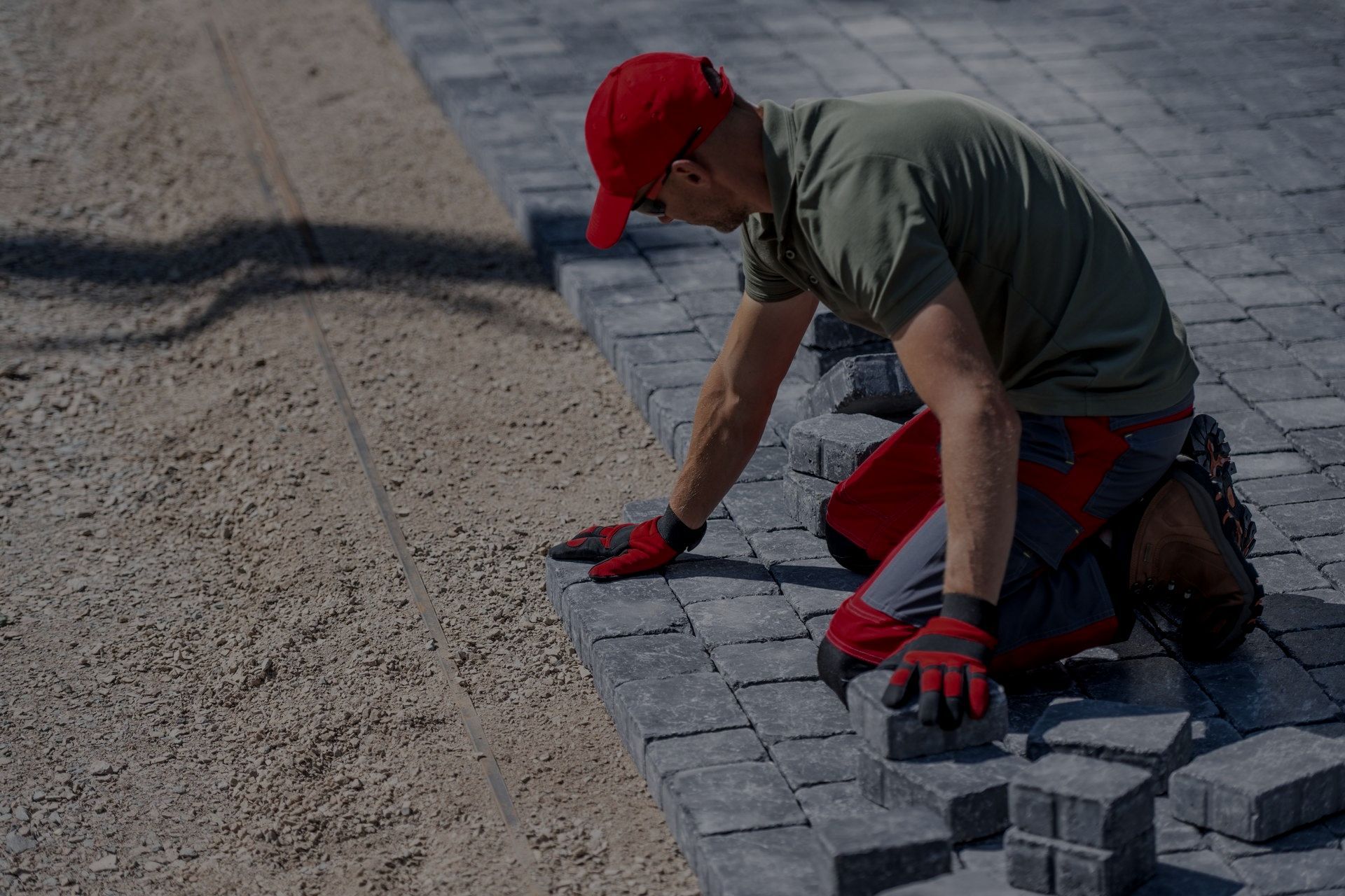 A man is laying bricks on a sidewalk.