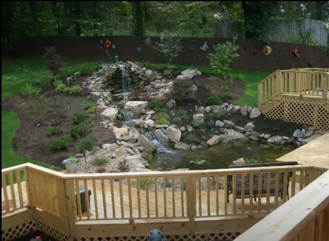 A wooden deck with a waterfall in the backyard