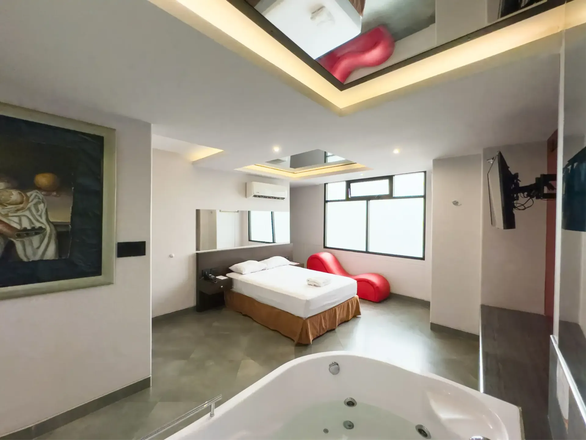Habitación decorada con cuadros, tv, aire acondicionado y jacuzzi