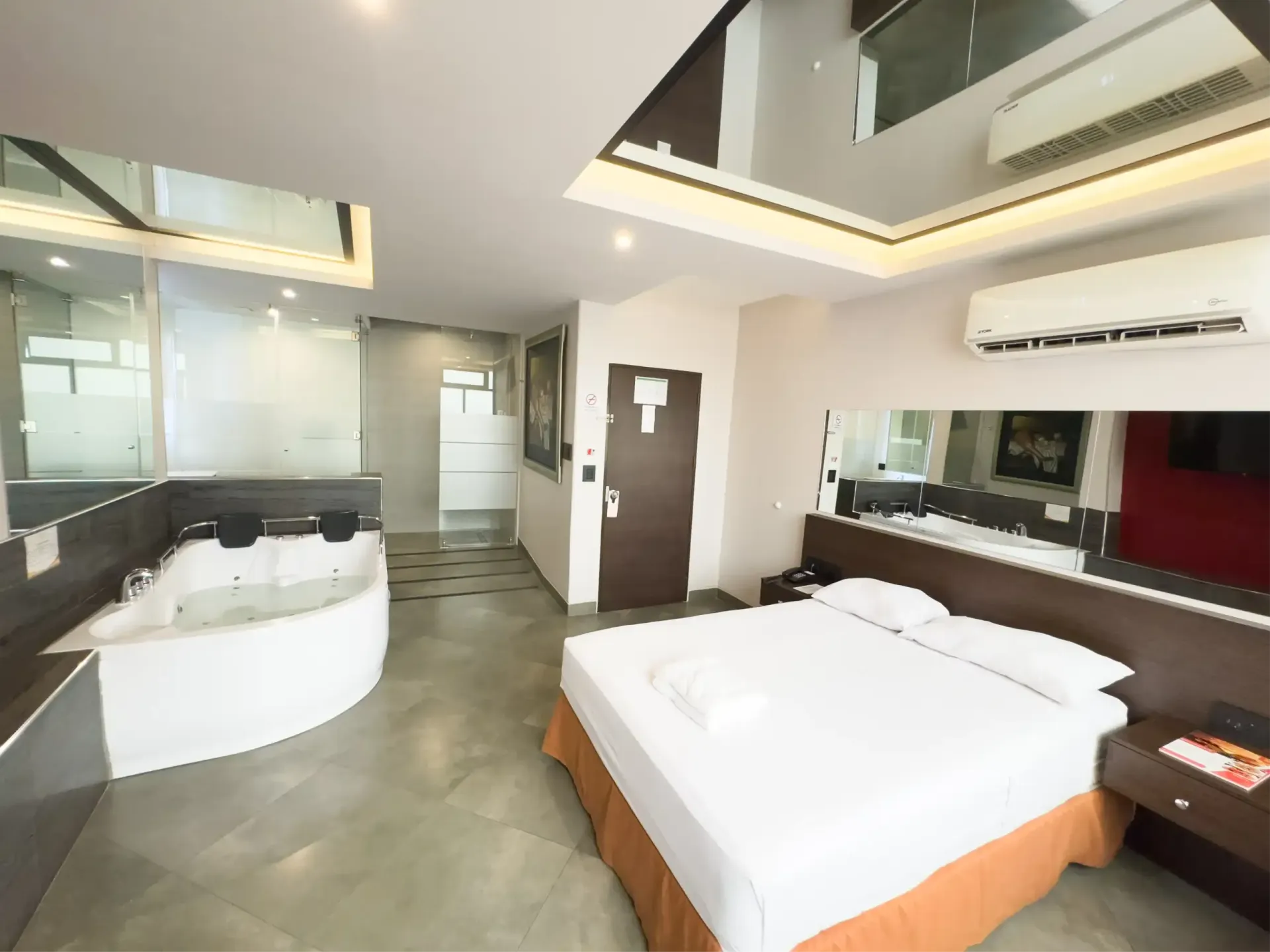 Habitación decorada con cuadros, tv, aire acondicionado y jacuzzi