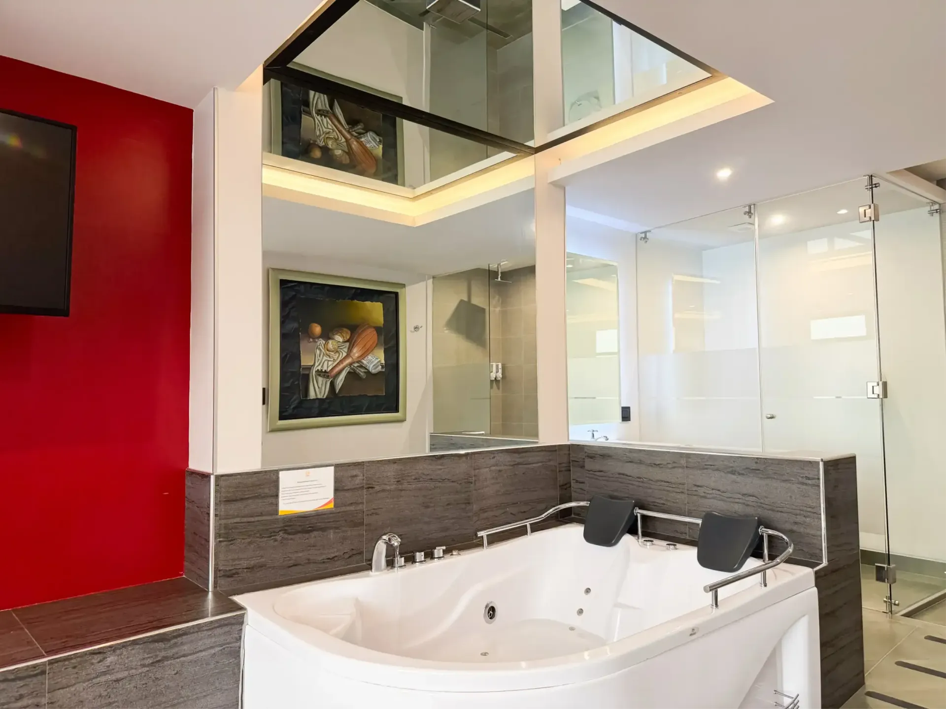 Habitación decorada con cuadros, tv, aire acondicionado y jacuzzi