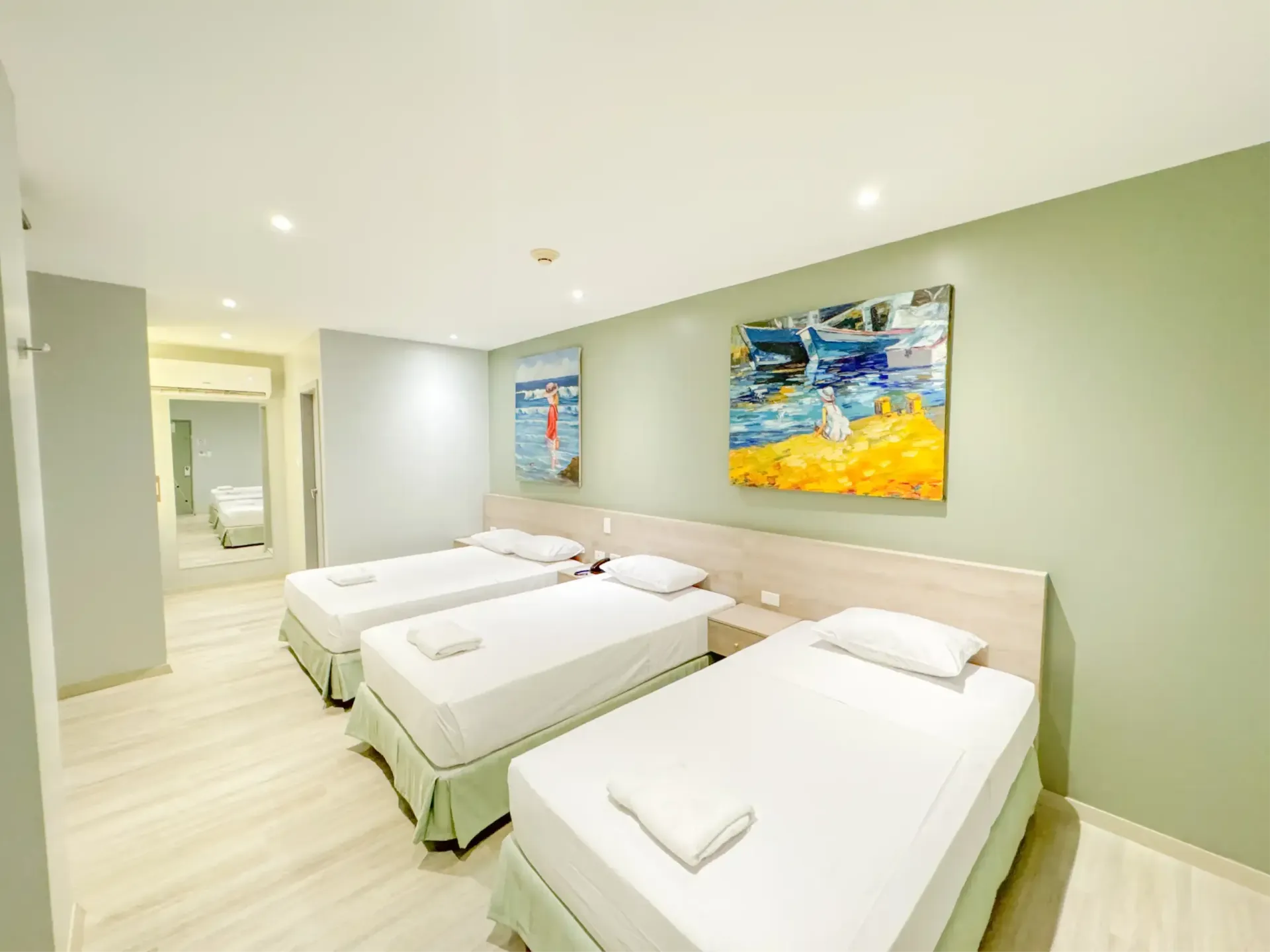 Una habitación de hotel con tres camas y dos pinturas en la pared
