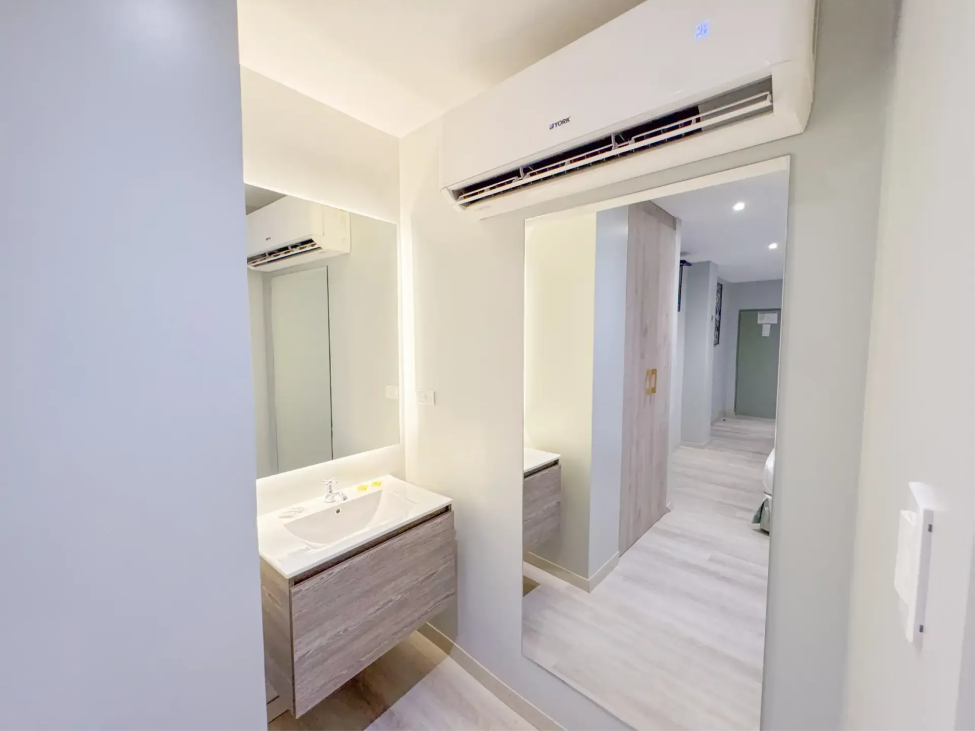 Una habitación de hotel con dos camas, un espejo y una ventana