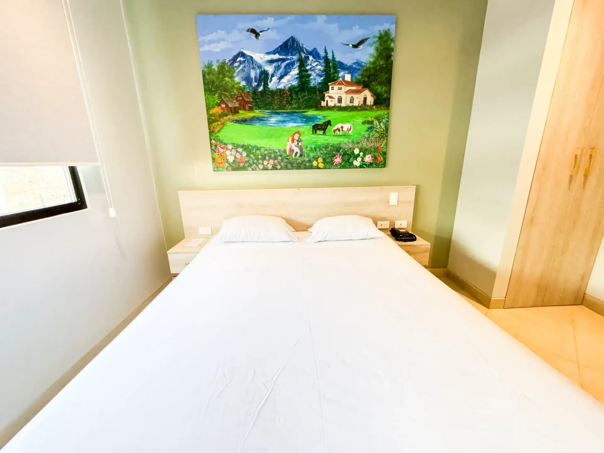 Un dormitorio con una cama y una pintura en la pared sobre ella