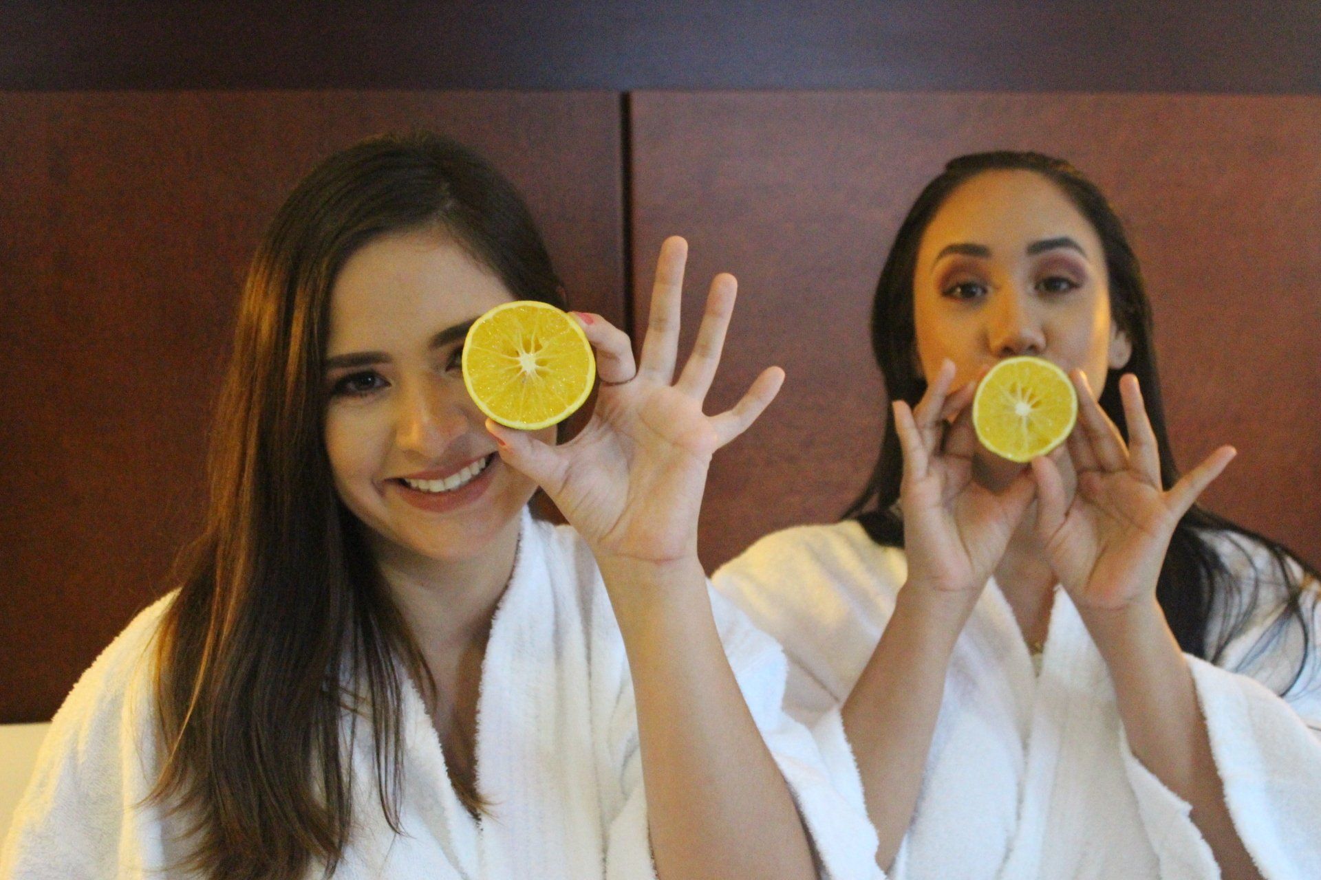 Dos mujeres están sosteniendo rodajas de limón frente a sus ojos