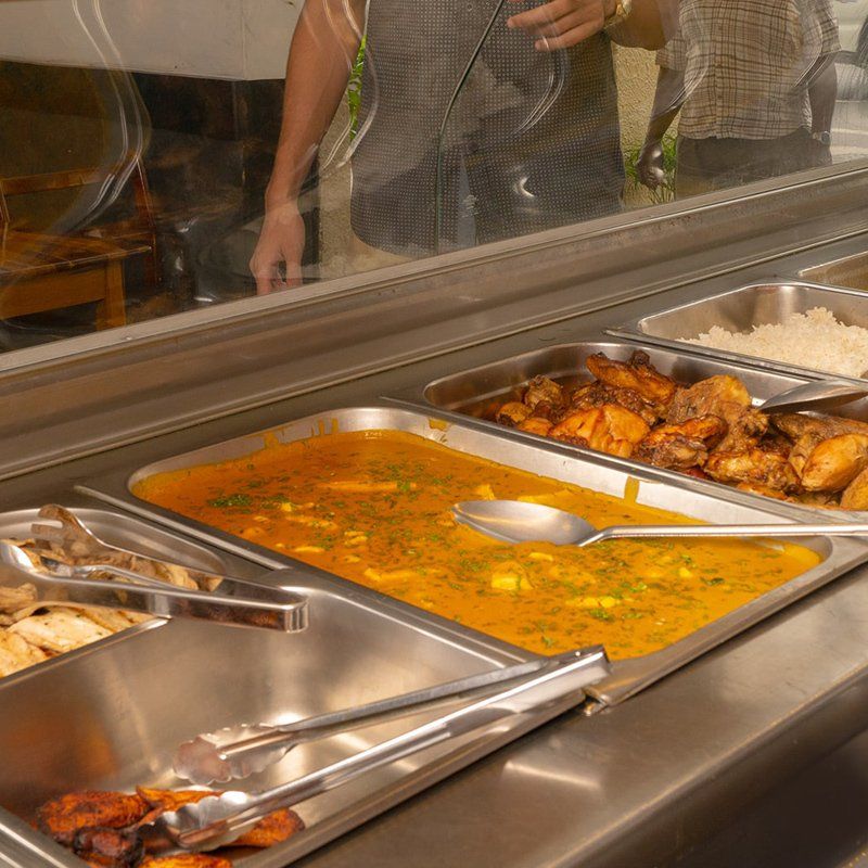 Una fila de buffet con una variedad de alimentos, incluyendo pollo y arroz