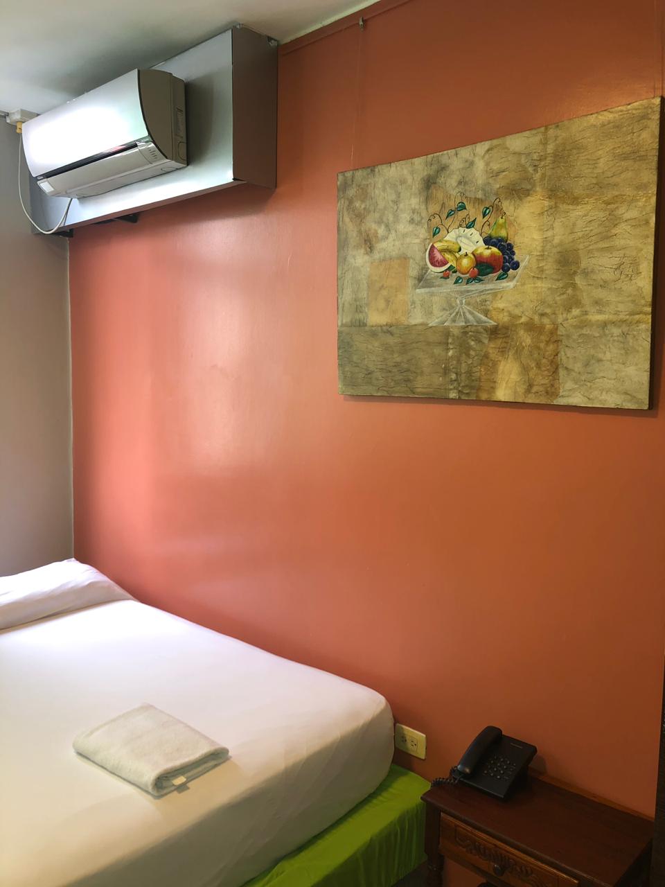 Dormitorio con una cama y una pintura sobre una pared roja