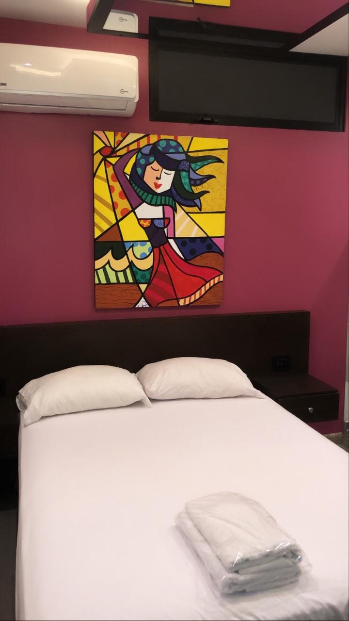 Una cama con una pintura abstracta en la pared encima de ella