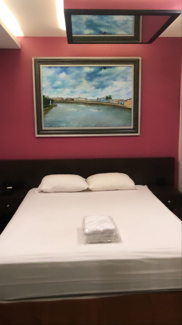 Una cama con una imagen en la pared morada encima de ella