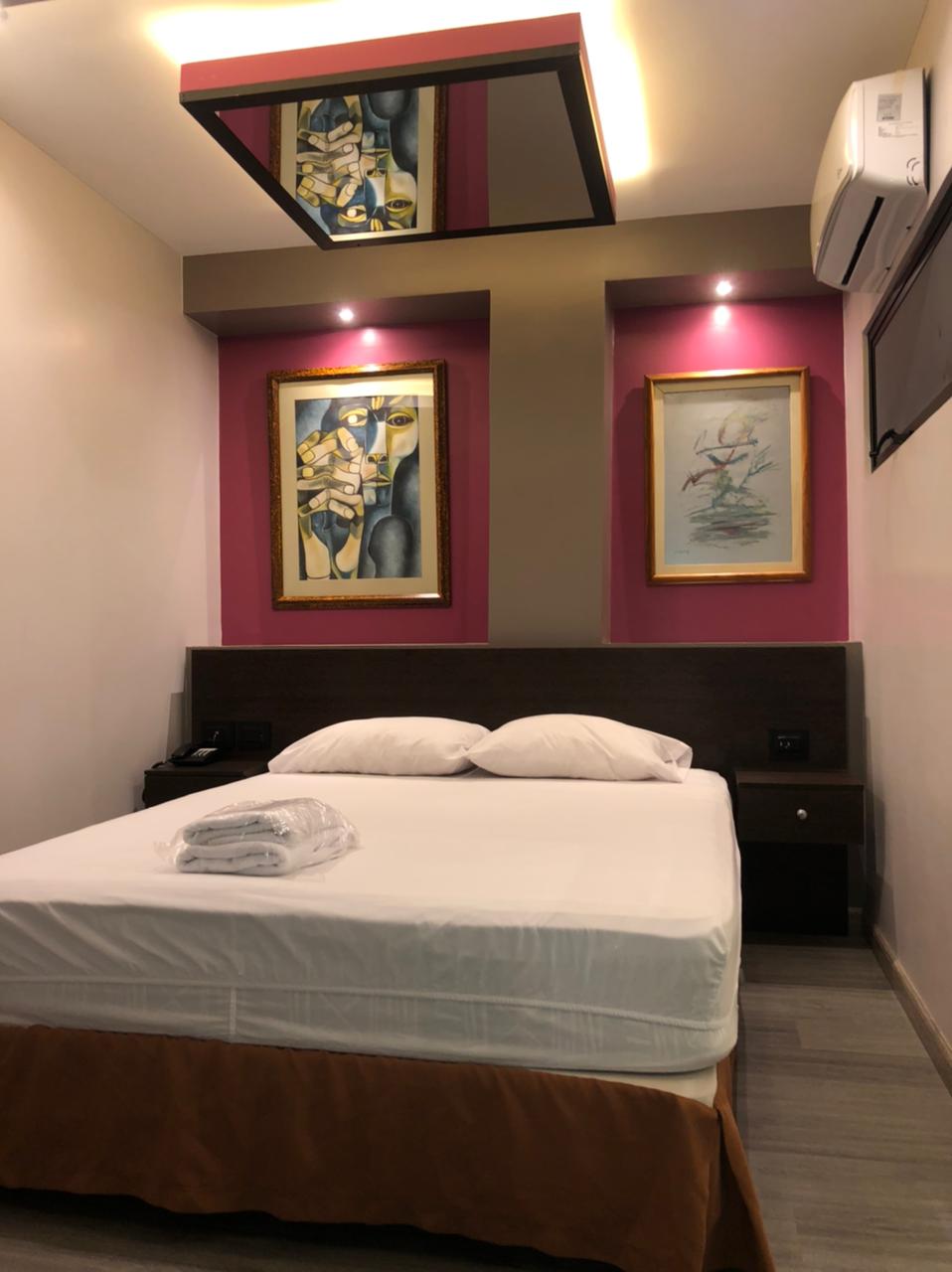 Una habitación de hotel con una cama y dos pinturas en la pared