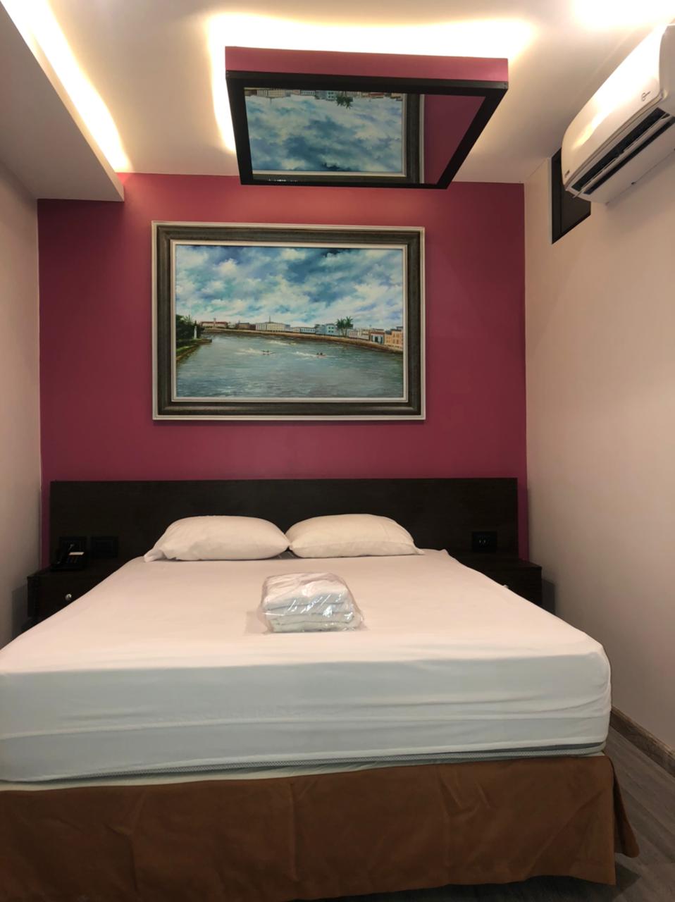 Un dormitorio con una cama y un cuadro en una pared morada