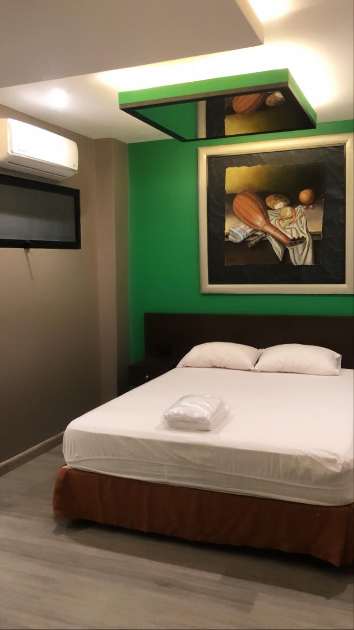 Una habitación de hotel con una cama y una imagen en la pared verde