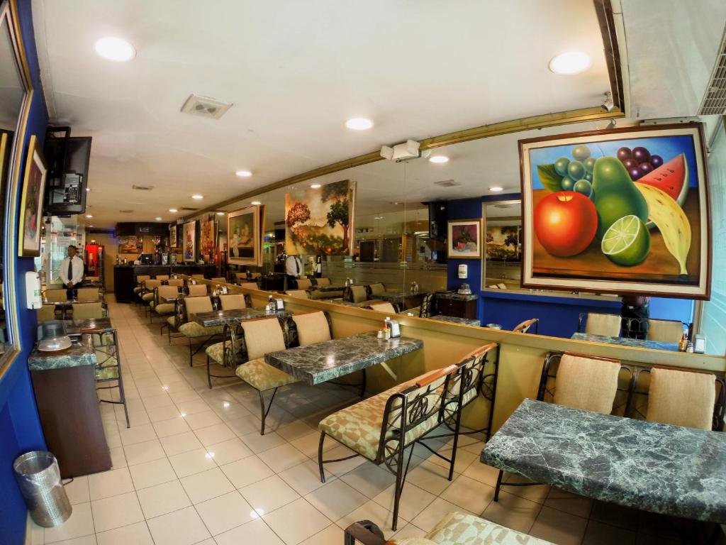 Un restaurante con mesas y sillas, y una pintura de frutas en la pared