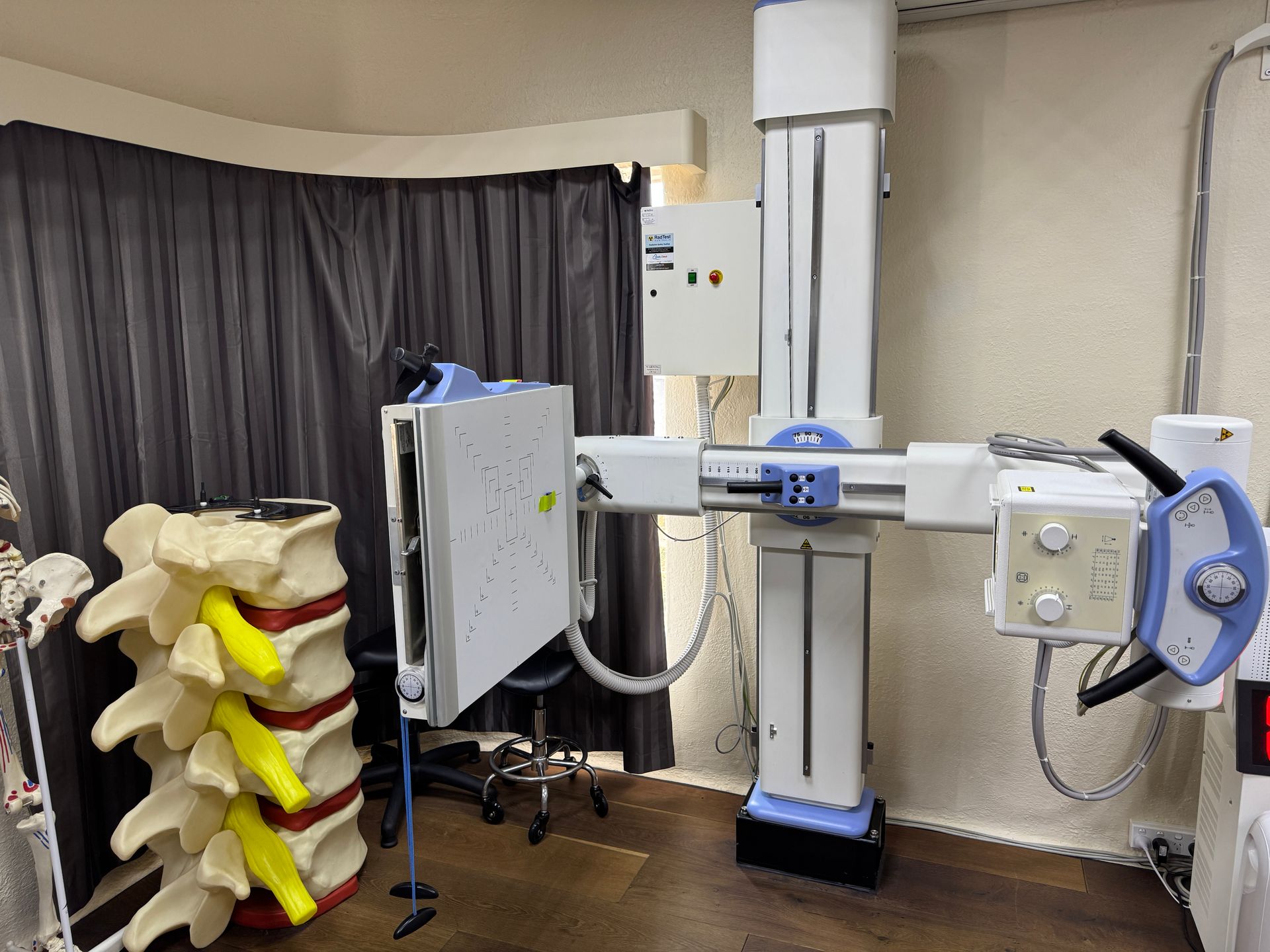 X-ray machine in a medical office next to a spinal model. White and blue equipment.