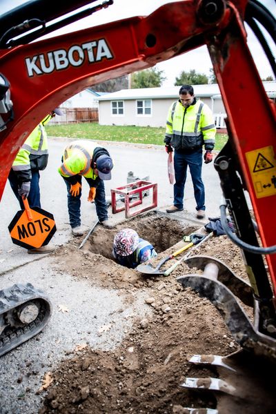 Underground crew repairing sewer pipes in hole on street