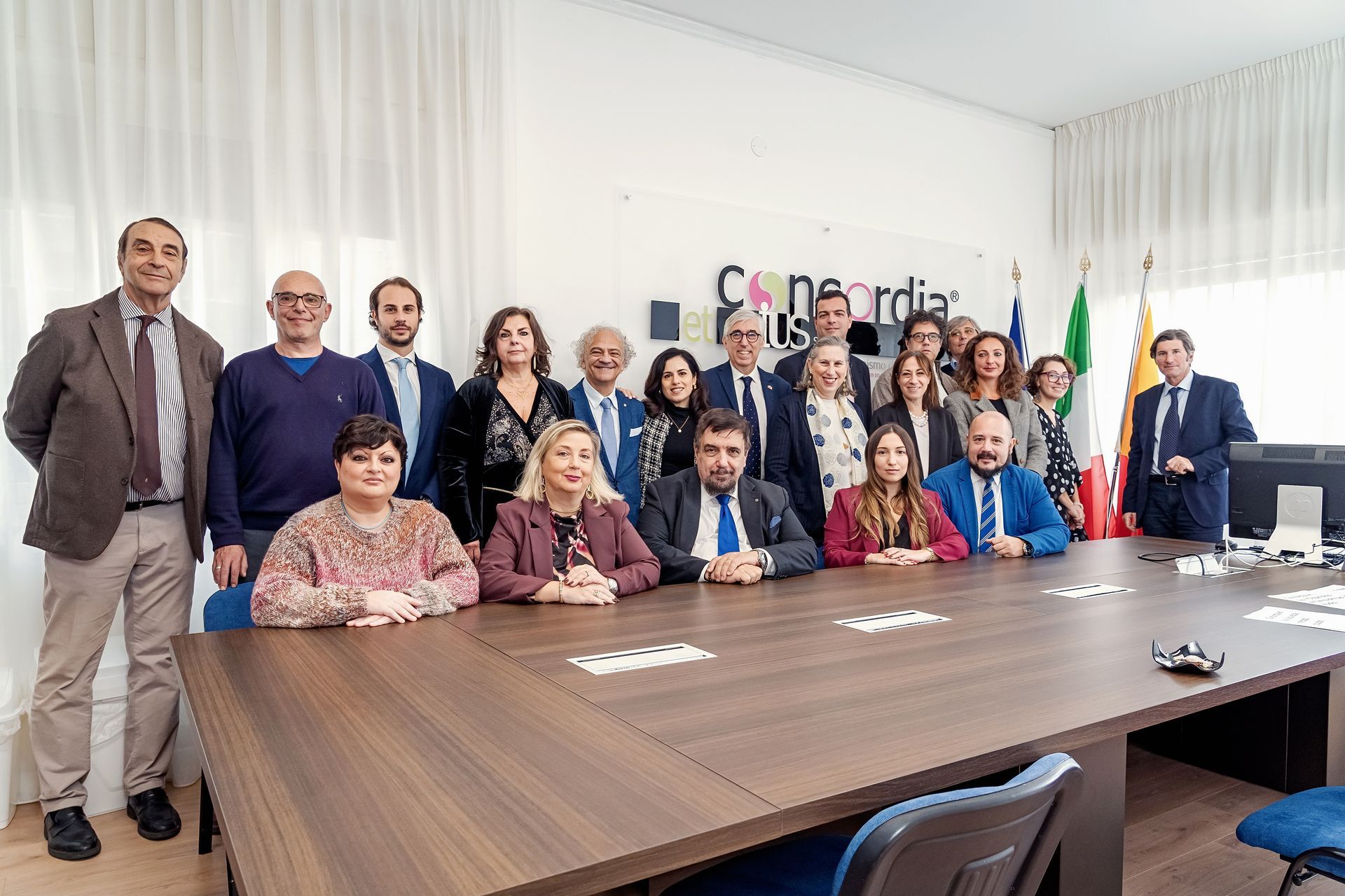 Gruppo di persone in una sala riunioni, in posa dietro un grande tavolo. La parola