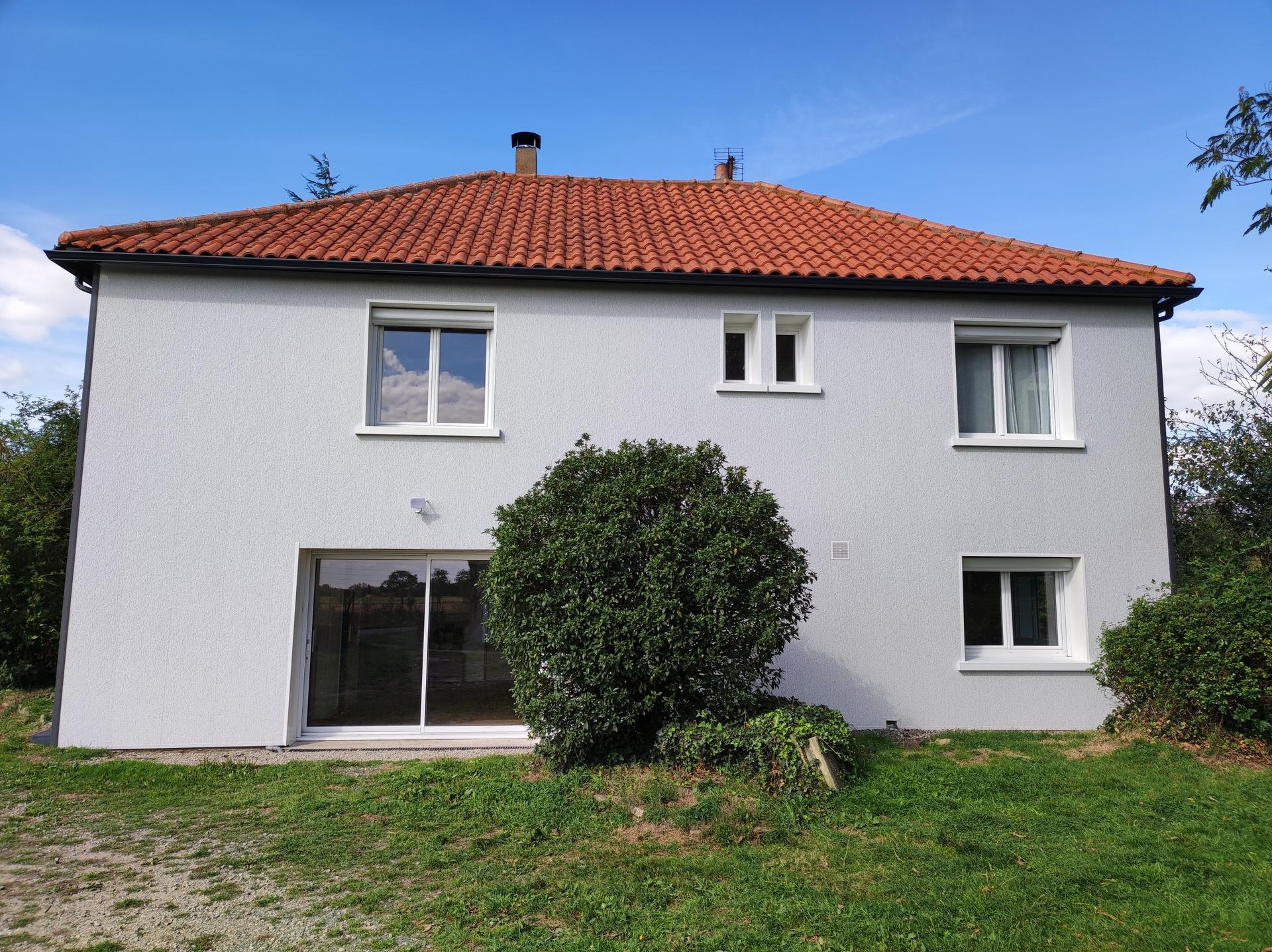 Une maison blanche avec un toit de tuiles rouges