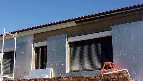 Une maison est en construction avec un toit rouge et une échelle devant.