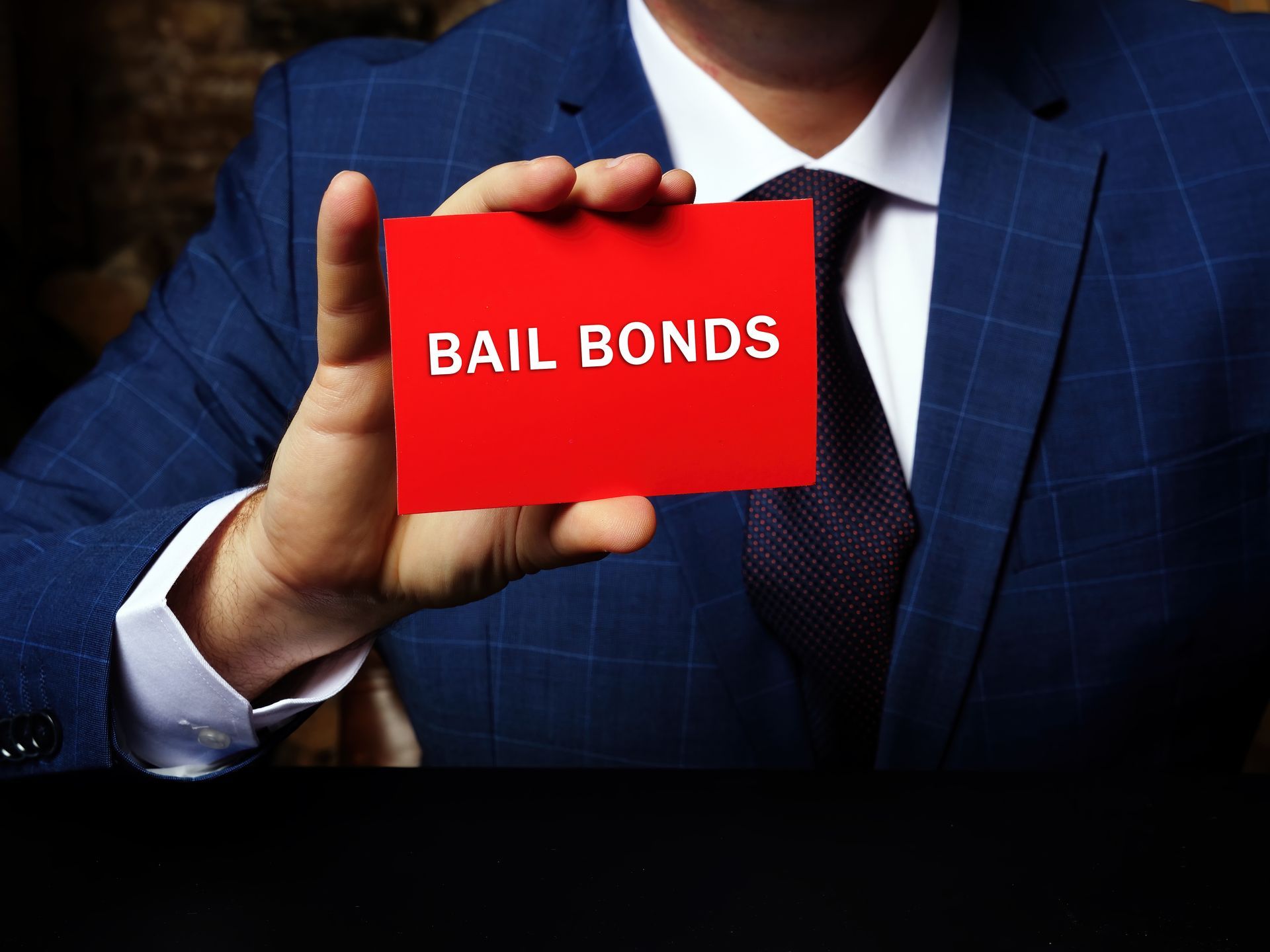 Person in suit holding a red card with the words “BAIL BONDS.”