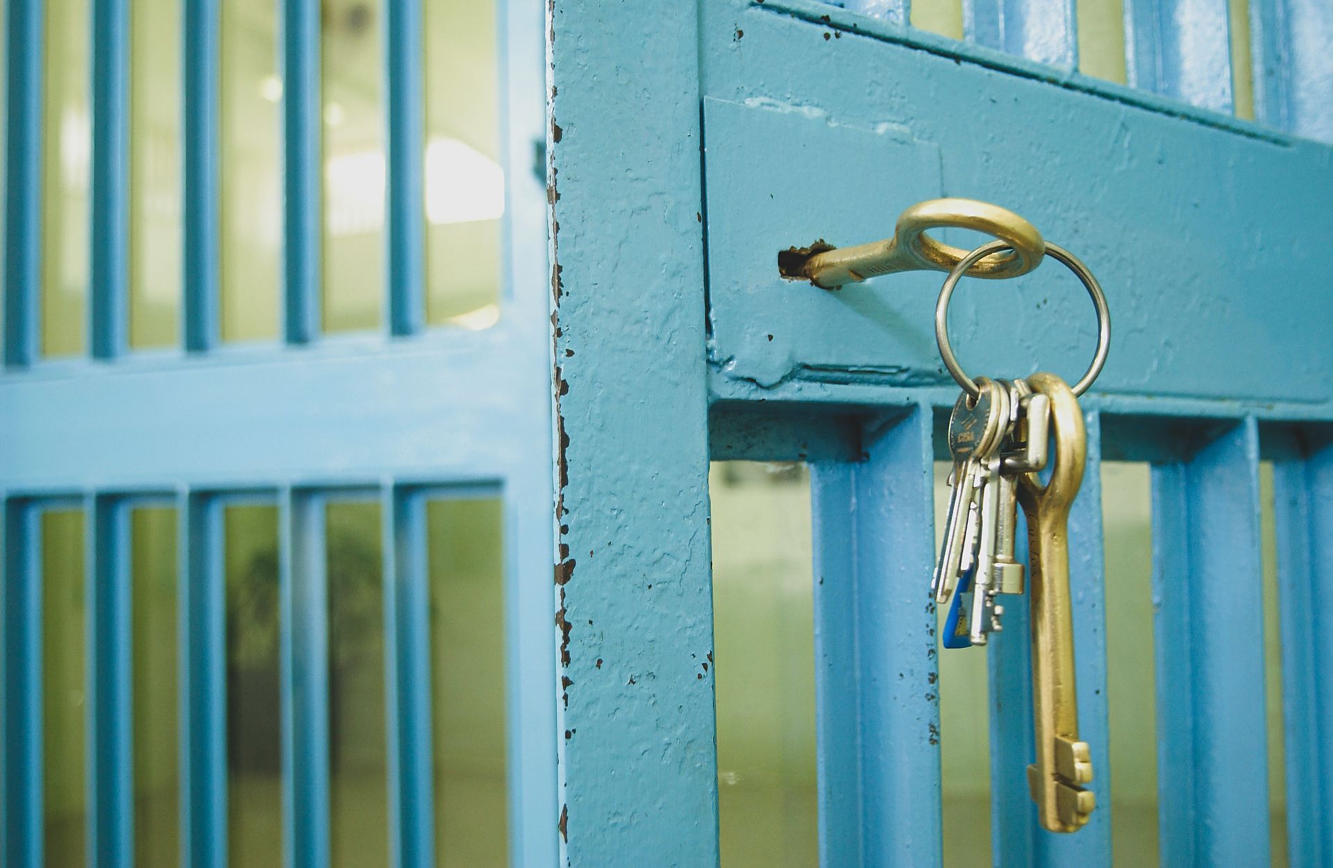 Blue jail cell door with a key ring hanging in the lock.